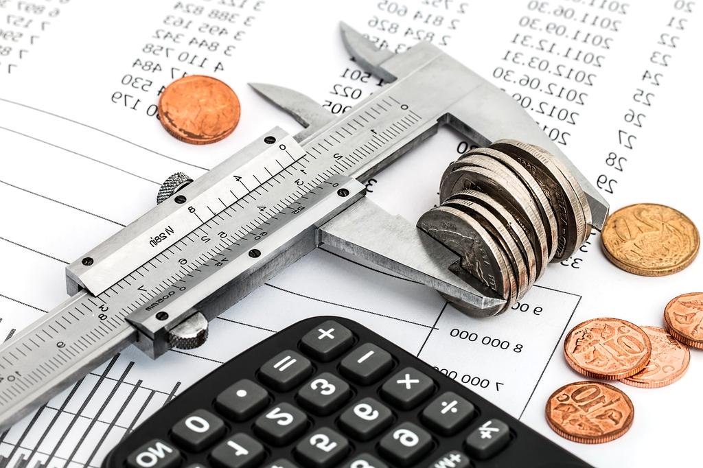 Person reviewing a household budget notebook and calculator at a kitchen table